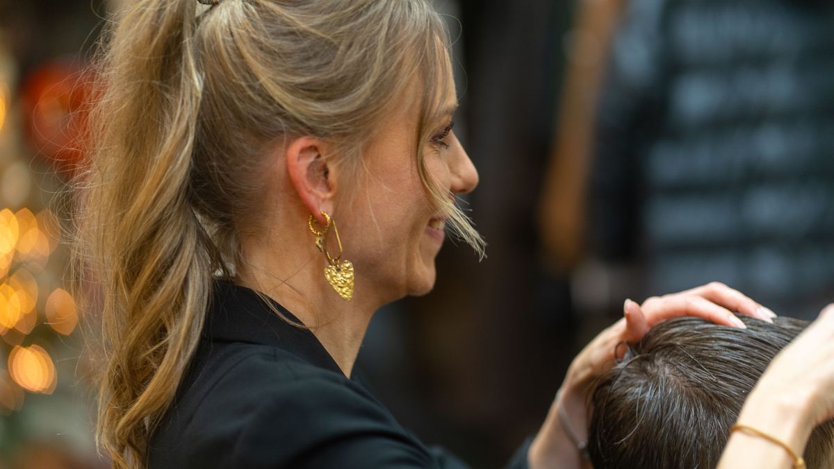 Stylistin prüft im Gespräch die Haarstruktur eines Kunden — Beratung vor dem Schnitt